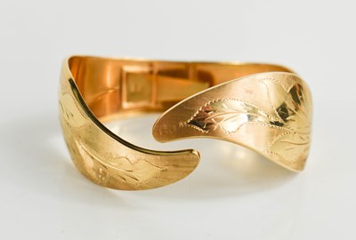 Lot 3 - An 18ct gold bangle, engraved with foliage and...