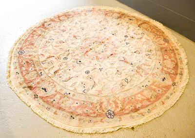 Lot 580 - A circular rug, with cream ground, decorated...