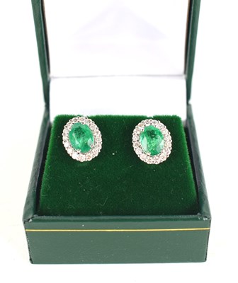 Lot 277 - A pair of 18ct white gold oval emerald and...