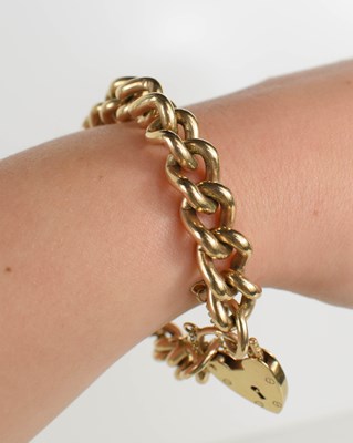 Lot 107 - A 9ct gold chain link bracelet with a heart...