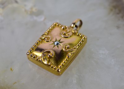 Lot 27 - A gold locket pendant with starburst diamond,...