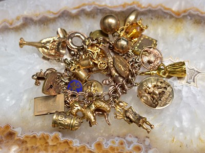 Lot 110 - A 9ct gold charm bracelet with twenty nine...