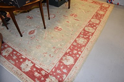 Lot 432 - Large pale green and cream rug with deep red...